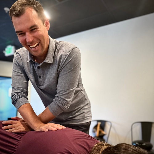 Dr. Brock Martin laughing with a patient during a chiropractic adjustment